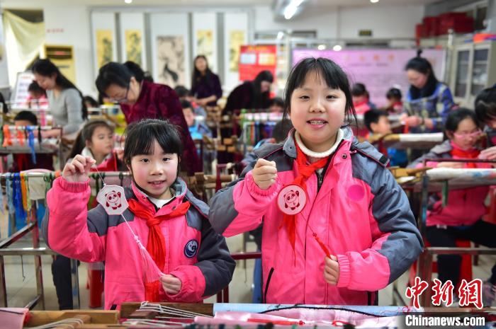 圖為小學(xué)生展示繡制好的2022年北京冬奧會吉祥物“冰墩墩”形象。　喻云亮 攝