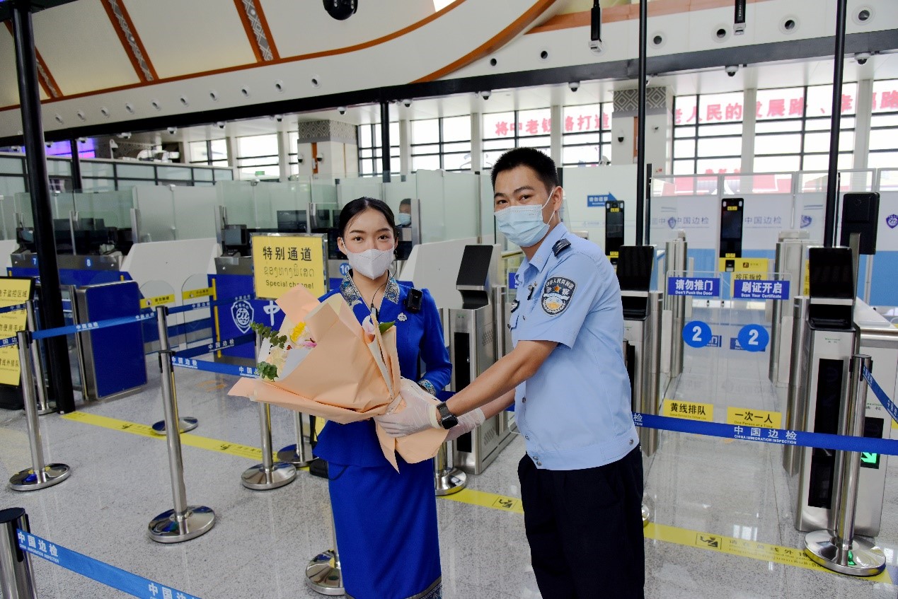 磨憨出入境邊防檢查站民警為中老鐵路第100萬(wàn)名出入境旅客，D888次國(guó)際旅客列車(chē)?yán)蠐爰藙?wù)員森達(dá)拉·妮緹婭（Sengdala Nitiya），送上鮮花。黃遠(yuǎn)飛 攝