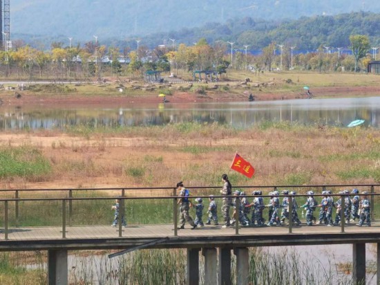 　　10月24日，秋游的幼兒園小朋友在老師帶領下走在清水塘公園里的木橋上。本報記者 常雯宜攝