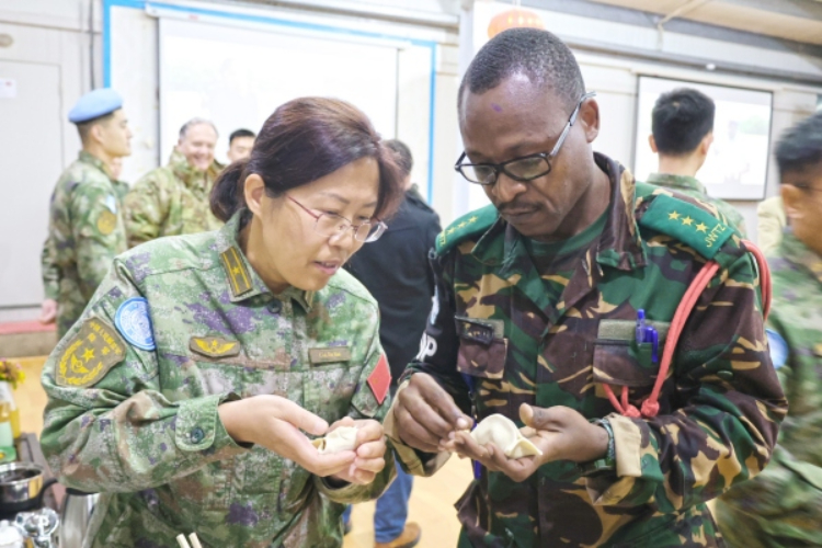 圖為維和官兵與外軍人員共同包餃子。胡光明攝