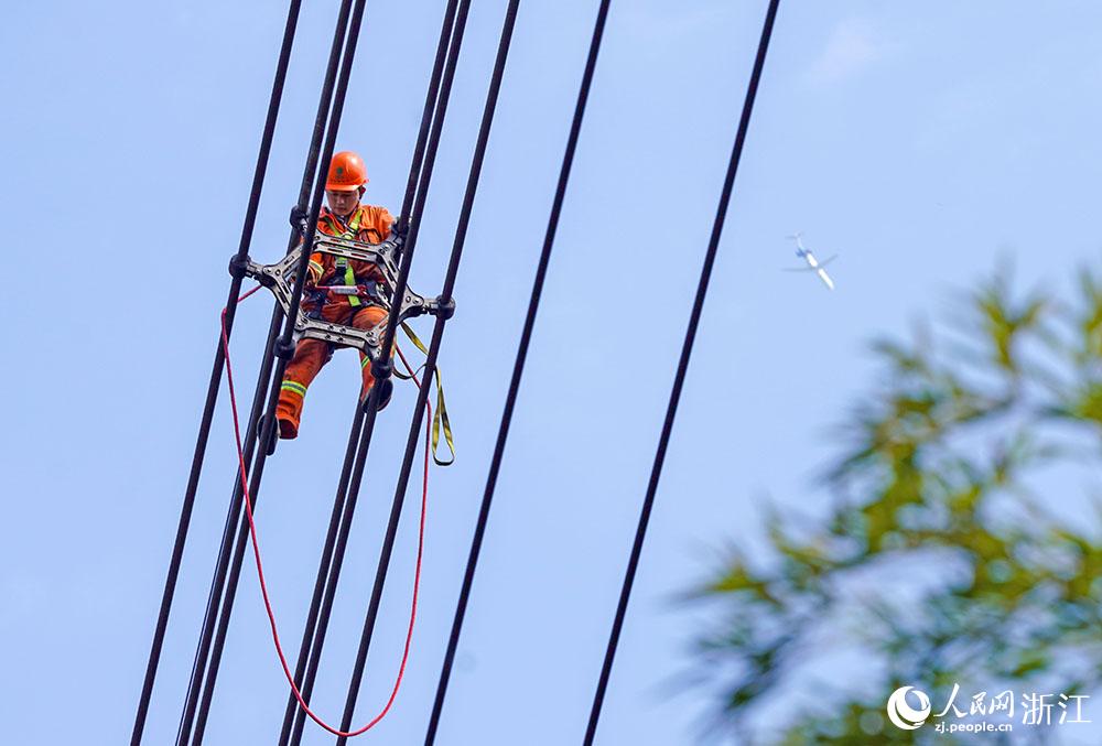 3月11日，在浙江省諸暨市河上鎮(zhèn)，浙江省送變電工程有限公司檢修人員在高空的導(dǎo)線上進(jìn)行線路檢修維護(hù)。人民網(wǎng) 章勇濤攝