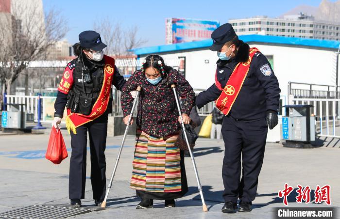 圖為拉薩鐵路公安民警幫助老人進(jìn)站乘車?！『铲i 攝