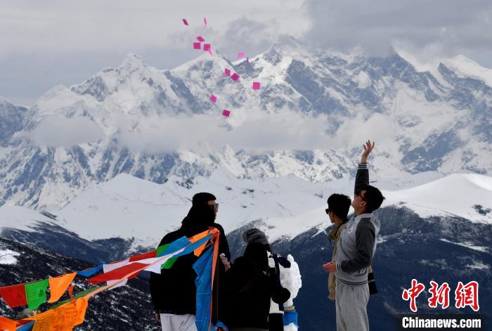 圖為5月14日，游客在西藏林芝色季拉山觀景臺(tái)拋灑“隆達(dá)”(風(fēng)馬旗，藏族民眾的一種祈福方式)?！±盍?攝