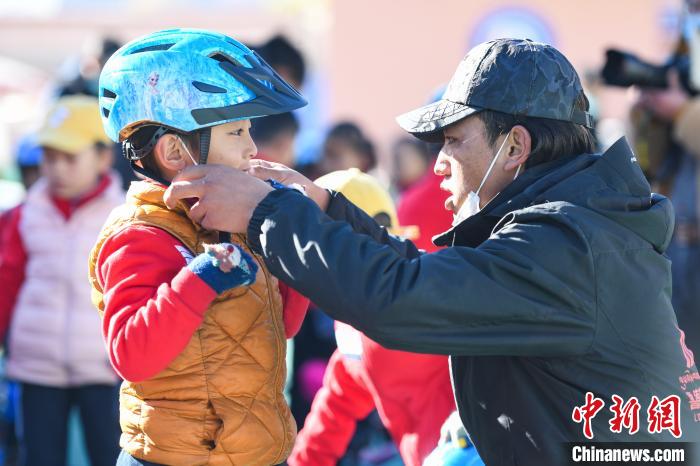 圖為拉薩市實(shí)驗(yàn)幼兒園孩子在教練的幫助下穿戴頭盔?！『闻罾?攝